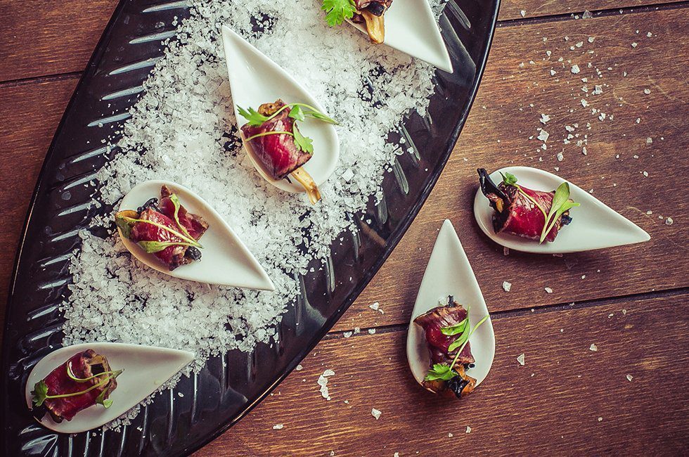 Beef canapés served on a black tray.