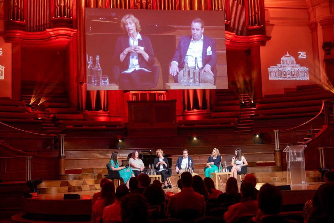 A panel speaking on stage in the Great Hall