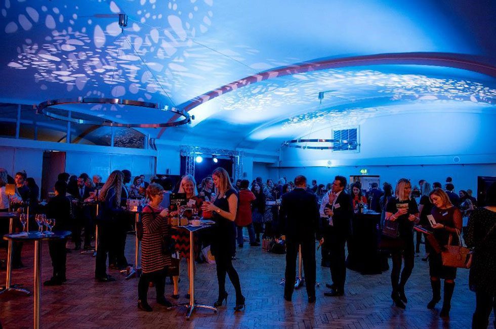 Guests at evening reception in Aldersgate Room, lit in blue